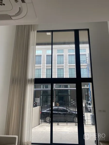 联排别墅 出租或出售在Bang Khae, Bangkok - 采光充足的客厅，黑色框架的落地窗面向街景