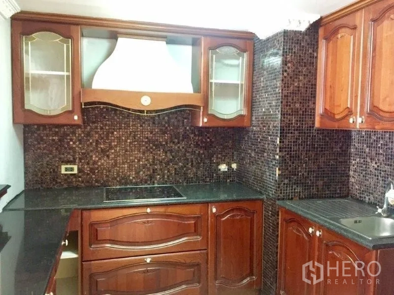 Condominium for rent or sale in Pathum Wan, Bangkok - U-shaped kitchen with mosaic backsplash, granite countertops, electric cooktop and sink.