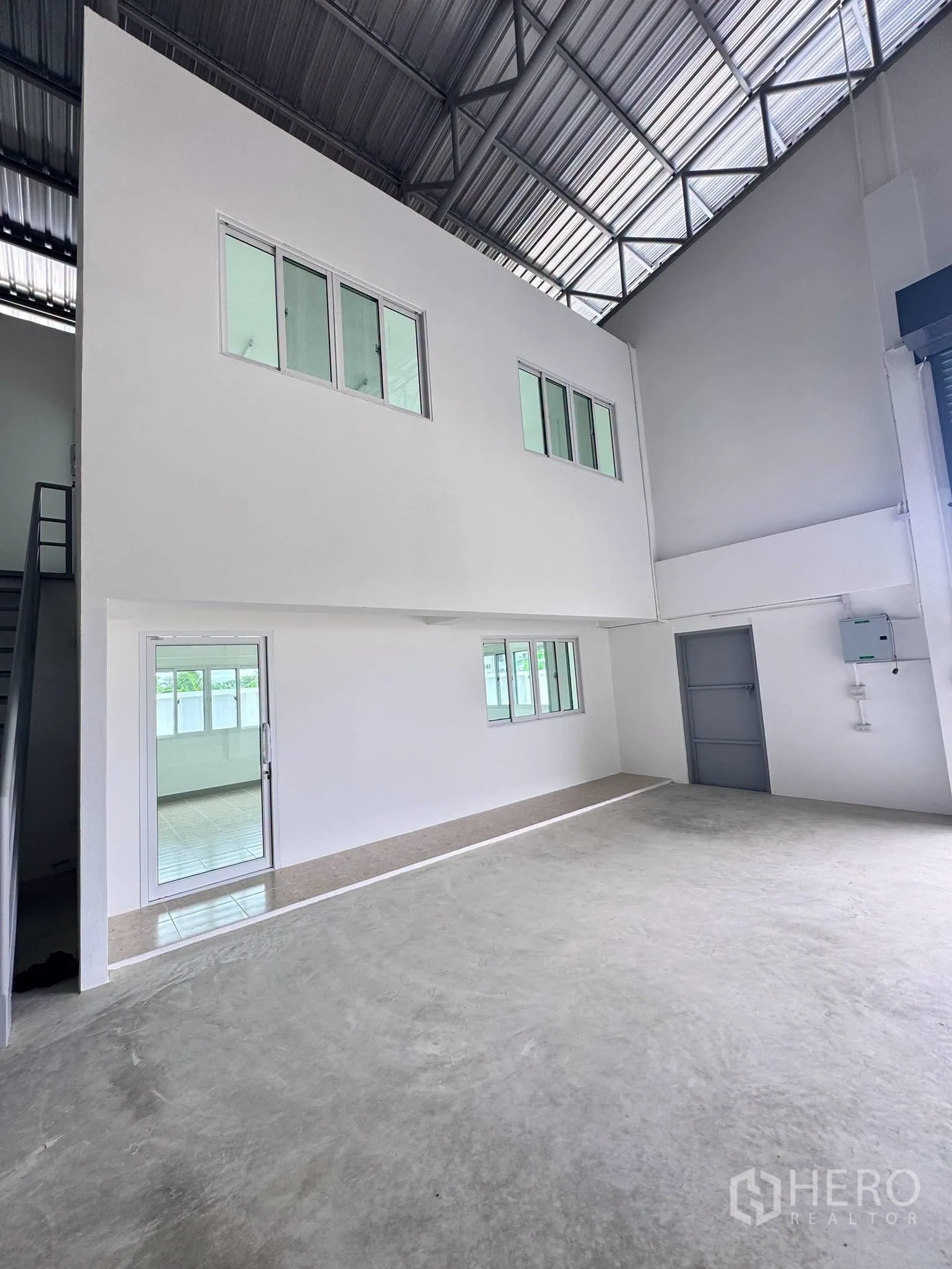Warehouse for rent in Bang Bo, Samut Prakan - Warehouse interior with mezzanine office block, windows, and concrete floor under a high truss roof.
