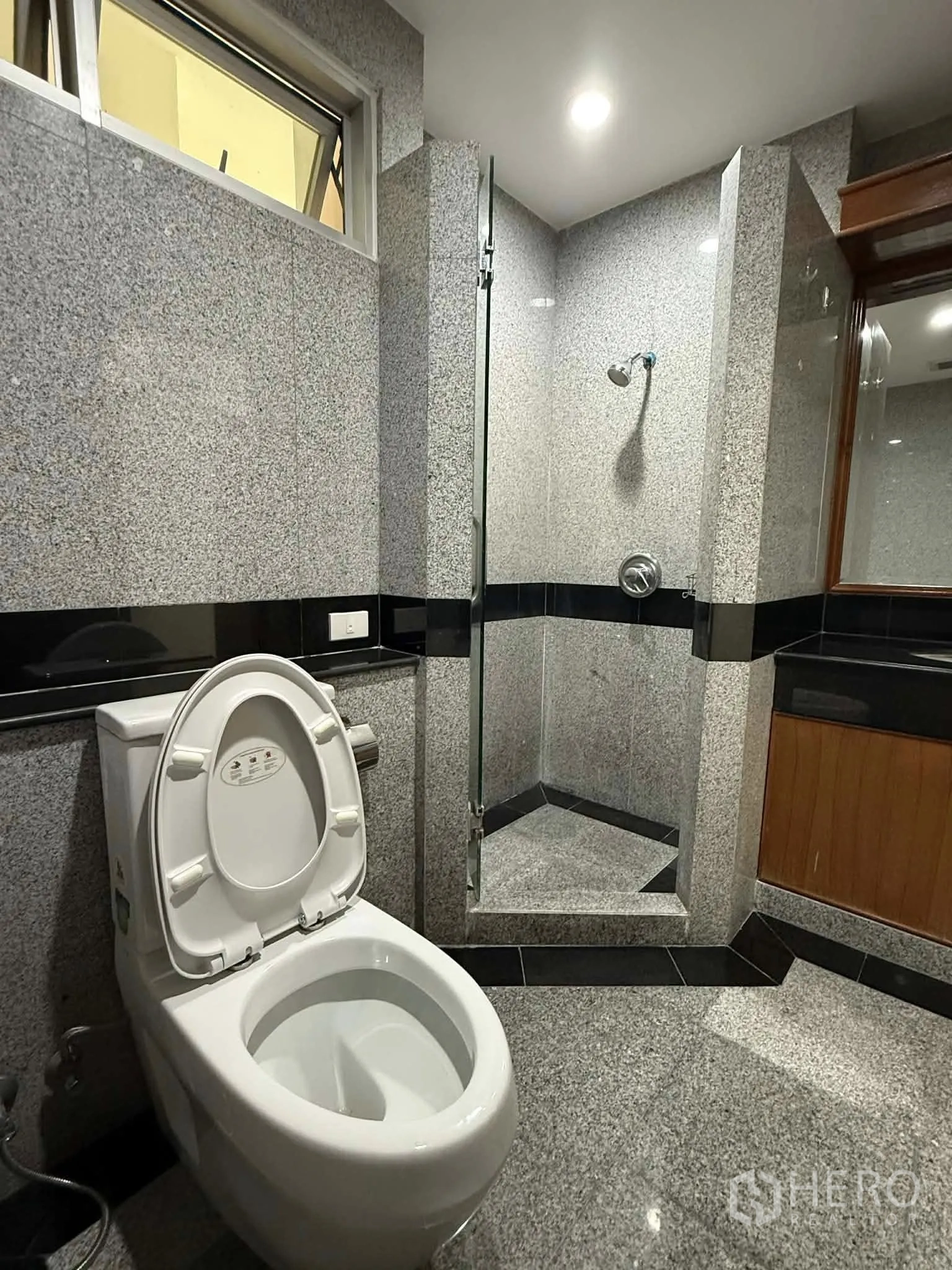 Condominium for rent in Pathum Wan, Bangkok - Bathroom with glass-enclosed shower, toilet, and vanity unit.