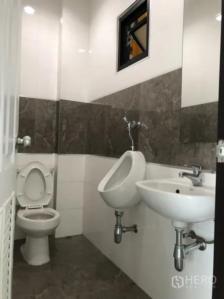 Factory for rent or sale in Bang Phli, Samut Prakan - Clean tiled toilet room with sink, urinal, and mirror inside the office area.