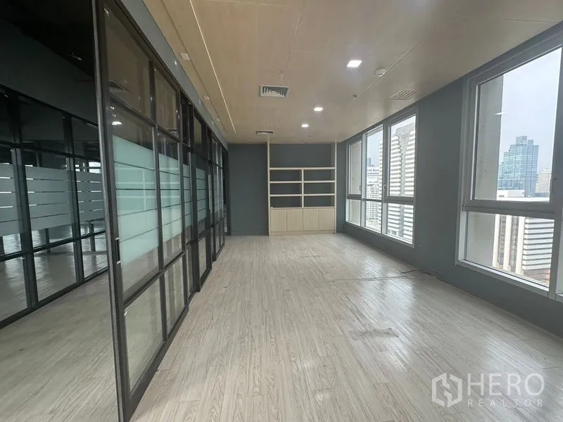 Office Space for rent in Bang Rak, Bangkok - Daylit room with built-in shelves, a glass wall, and skyline views.