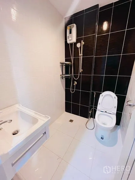Townhouse for rent in Huai Khwang, Bangkok - Modern bathroom with black accent wall, shower set and water heater.