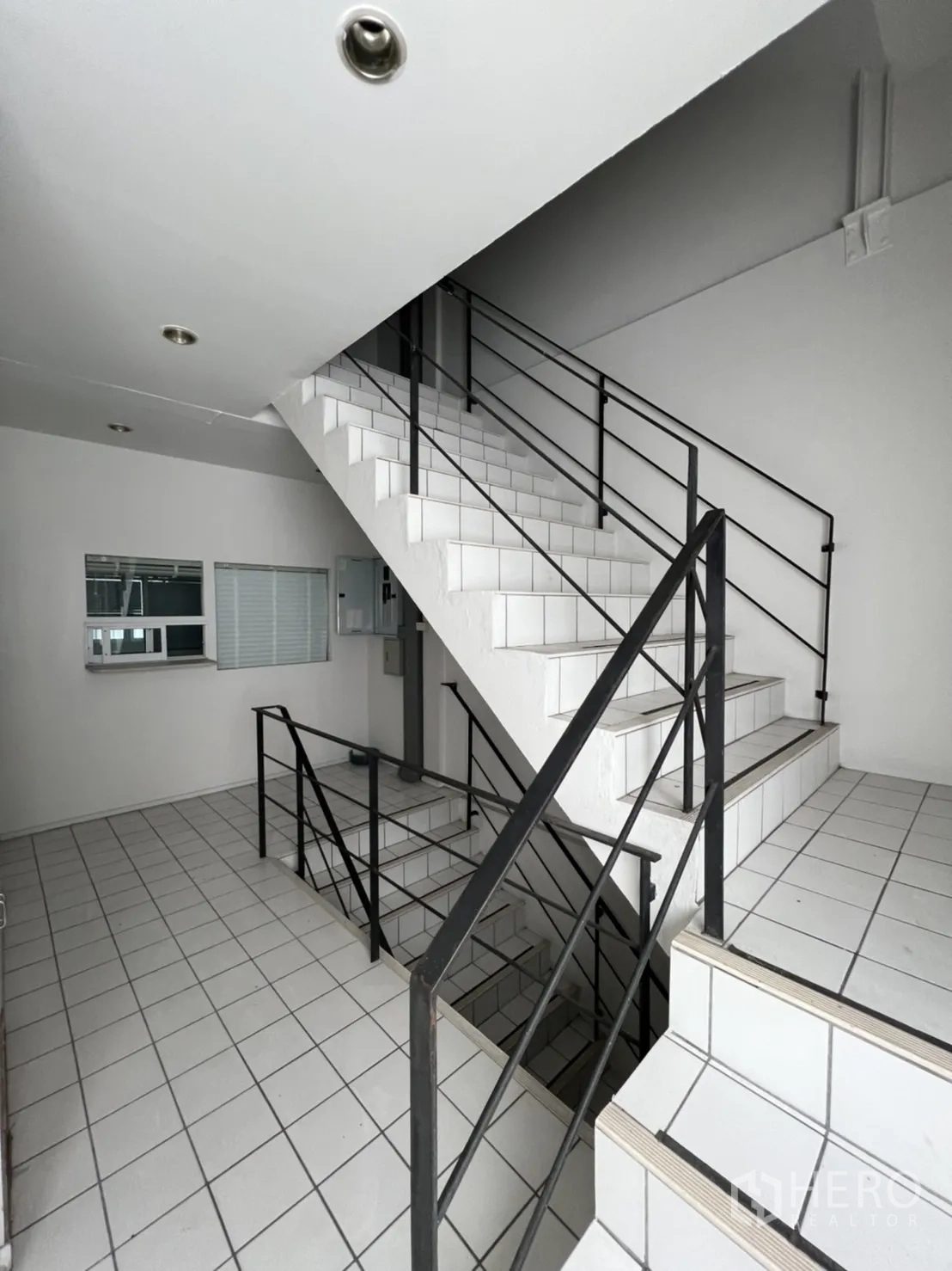 Shophouse for rent or sale in Watthana, Bangkok - Stairwell with white tiles and black metal handrails.
