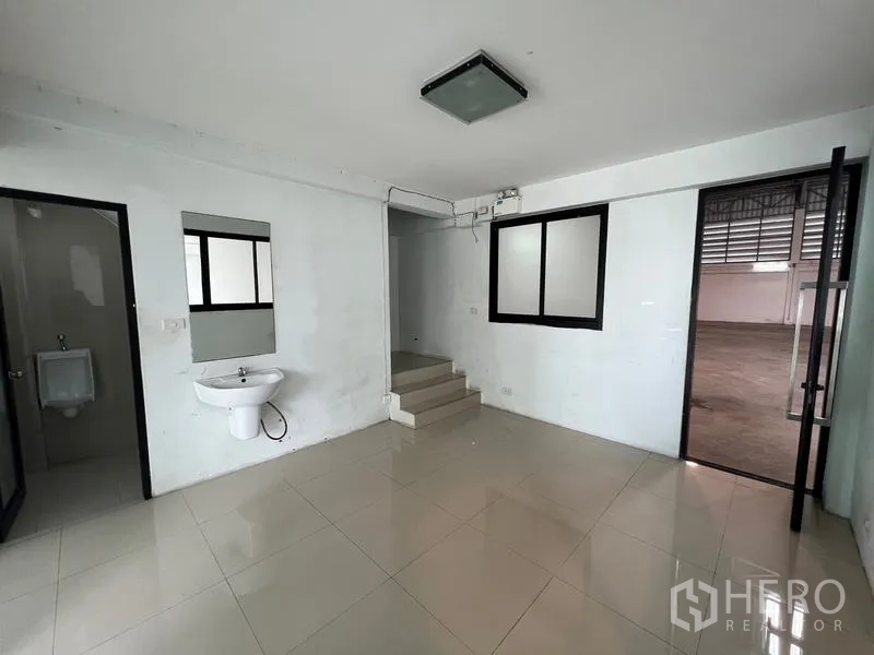 货栈 出租在Bang Phli, Samut Prakan - 一层办公室，带洗手池、卫生间入口与通往仓库的门。