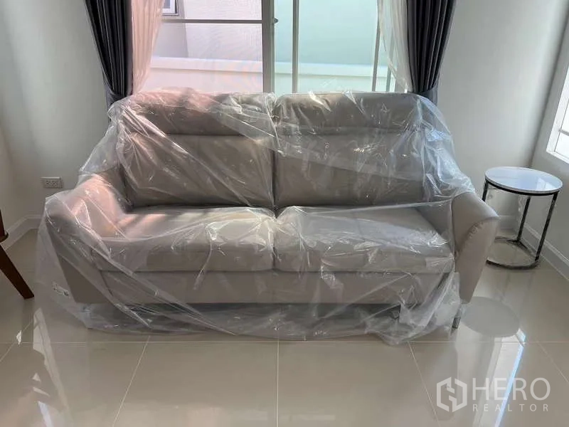 独立式住宅 出租在Bang Kapi, Bangkok - 明亮客厅内包膜的新灰色沙发。