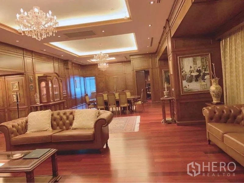公寓 出租在Watthana, Bangkok - 豪华客餐厅，木墙护板与格栅吊顶，水晶吊灯，皮沙发与实木地板。