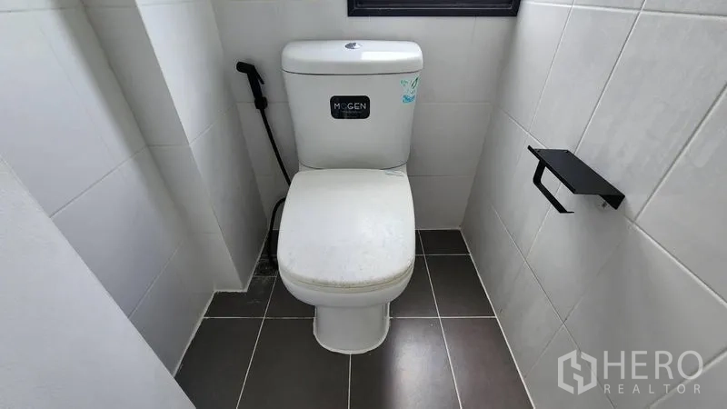 Home Office for rent - Compact restroom with toilet, bidet spray and tiled walls.