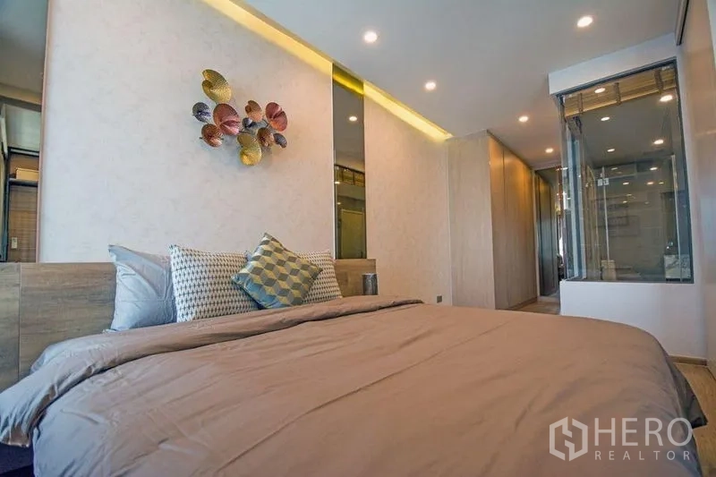 公寓 出售在Ratchathewi, Bangkok - 舒适卧室，配大床与靠枕，旁为玻璃墙浴室