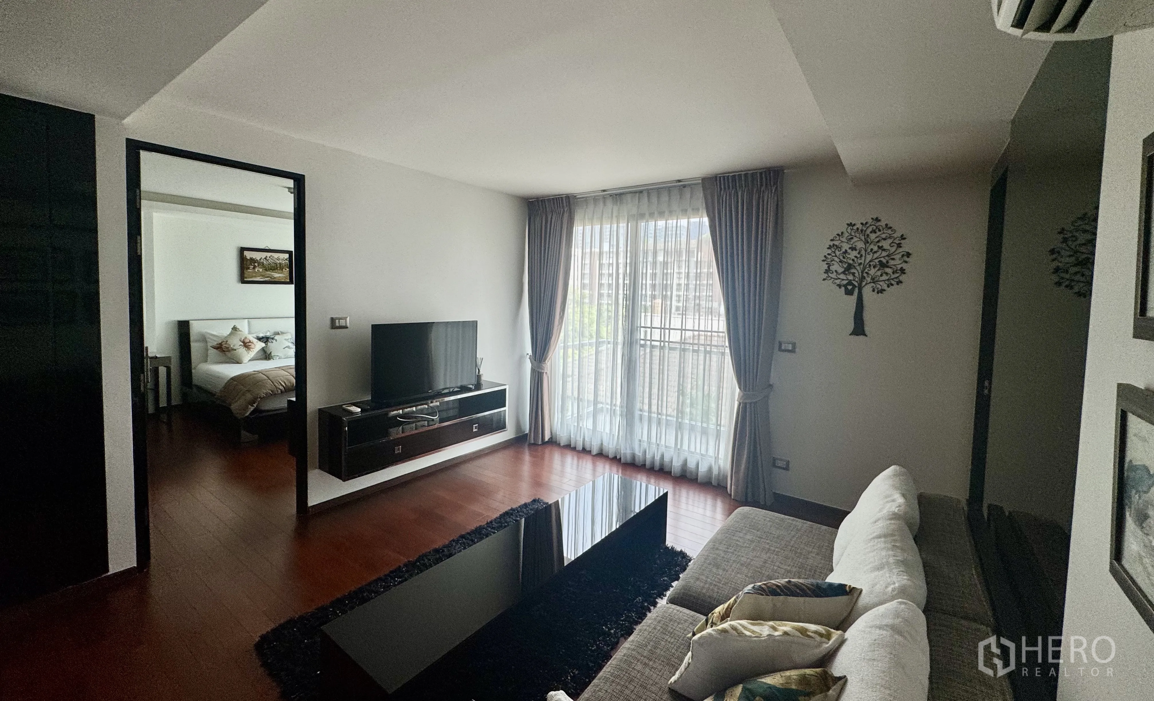 คอนโด for rent in Watthana, Bangkok - ห้องนั่งเล่นมีประตูกระจกออกระเบียง ผ้าม่านโปร่ง ชั้นวางทีวี และโซฟา.