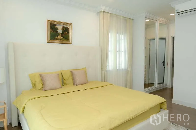 Detached House for rent or sale in Saphan Sung, Bangkok - Bedroom with mustard bedding, mirrored wardrobe and soft recessed lighting.