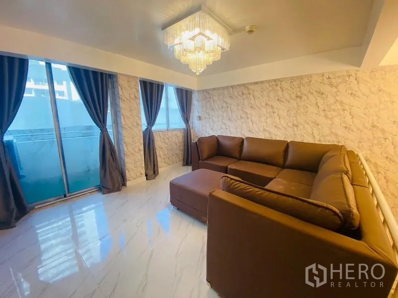 Condominium for rent or sale in Watthana, Bangkok - Secondary lounge with brown sectional sofa, floor-to-ceiling windows and chandelier.
