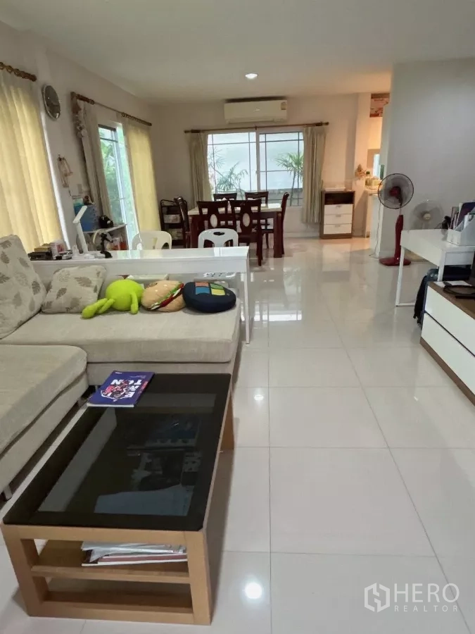 Detached House for sale in Bang Kapi, Bangkok - Open-plan living and dining area with sofa, glossy tile floors, and large windows.