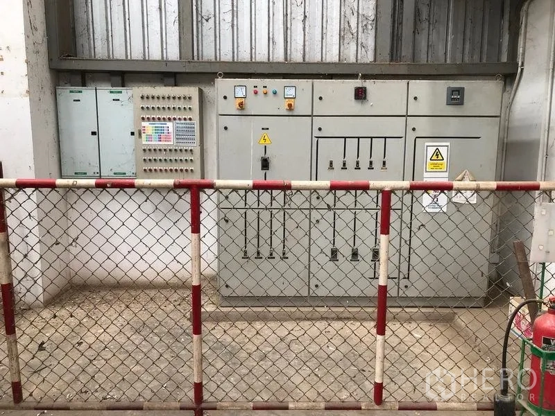 Factory for rent or sale in Lat Lum Kaeo, Pathum Thani - Electrical control panels behind a safety fence inside the factory.