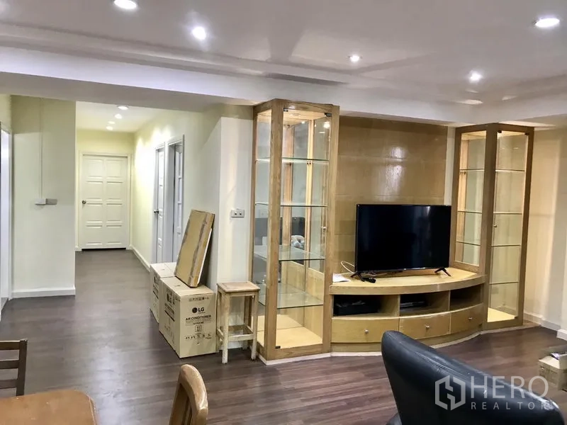 公寓 出租在Watthana, Bangkok - 客厅配玻璃展示柜、电视柜与木质地板，并连通走廊。