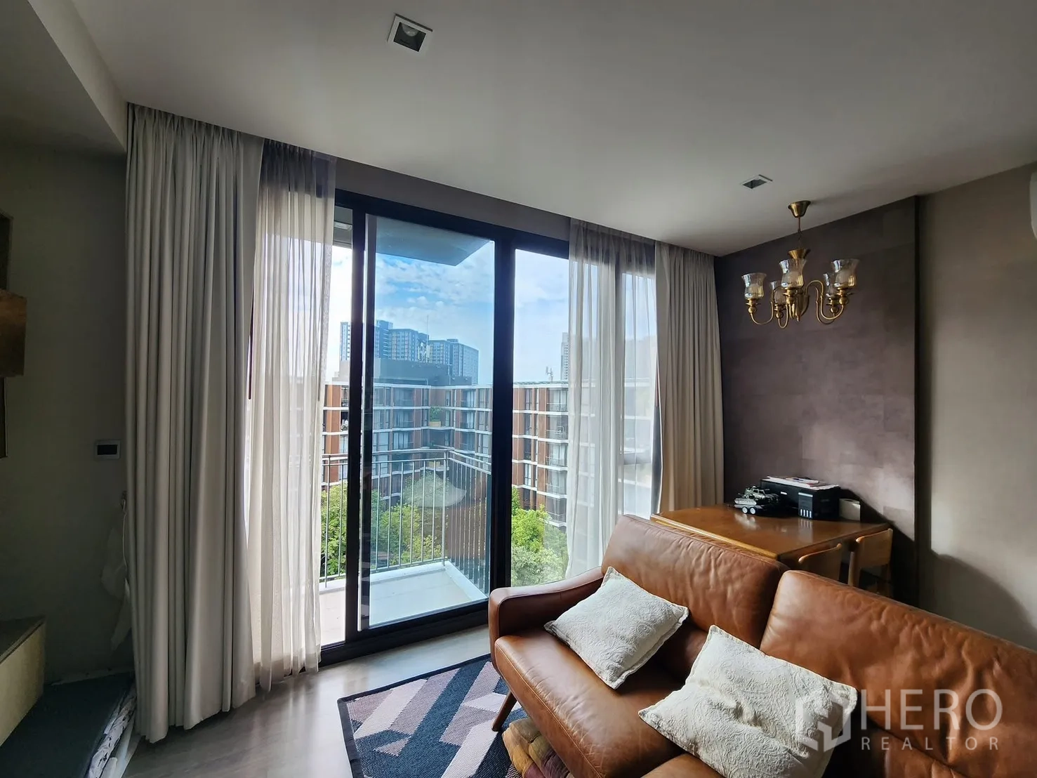 คอนโด for rent in Watthana, Bangkok - บริเวณโซฟาติดประตูกระจกระเบียง ผ้าม่านโปร่งและโคมระย้า มองเห็นวิวเมือง.