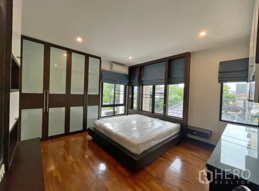 Detached House for rent in Chatuchak, Bangkok - Corner bedroom with wraparound windows and frosted-glass wardrobes.
