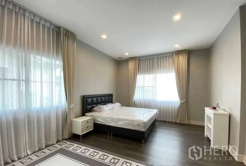 บ้าน ให้เช่าในBang Khen, Bangkok - ห้องนอนแขก เตียงหัวเตียงสีเข้ม พื้นไม้ และผ้าม่านสีอ่อน