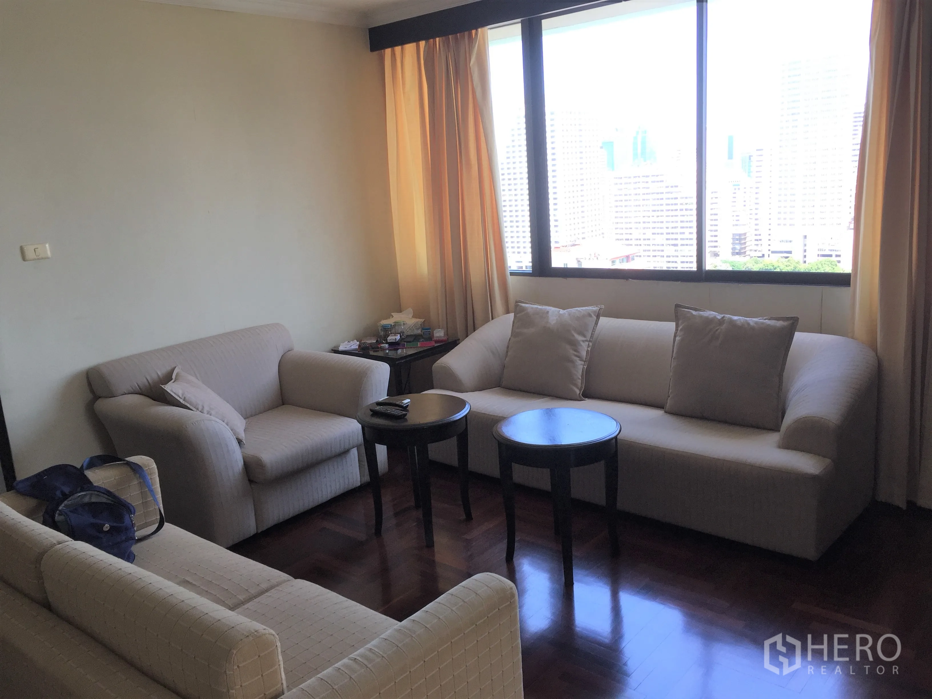 公寓 出租或出售在Khlong Toei, Bangkok - 舒适会客角，三张沙发与圆形茶几靠窗布置。