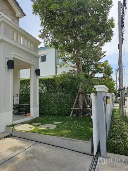 独立式住宅 出租在Prawet, Bangkok - 前院草坪与大树、绿篱及入户门