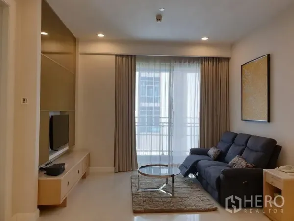 คอนโด ให้เช่าในPathum Wan, Bangkok - ห้องนั่งเล่นอบอุ่น โซฟา โต๊ะกลางทรงกลม และประตูกระจกสไลด์ออกระเบียง