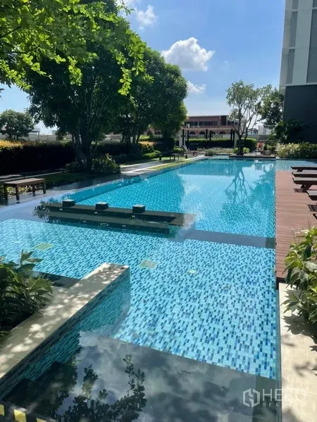 Condominium for sale in Phra Khanong, Bangkok - Outdoor lap pool with sun deck, trees and seating at a Bangkok condominium