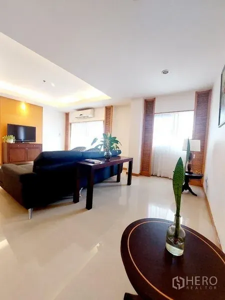 Apartment for rent - Bright living room with black sectional sofa, work desk, TV console and cove lighting.