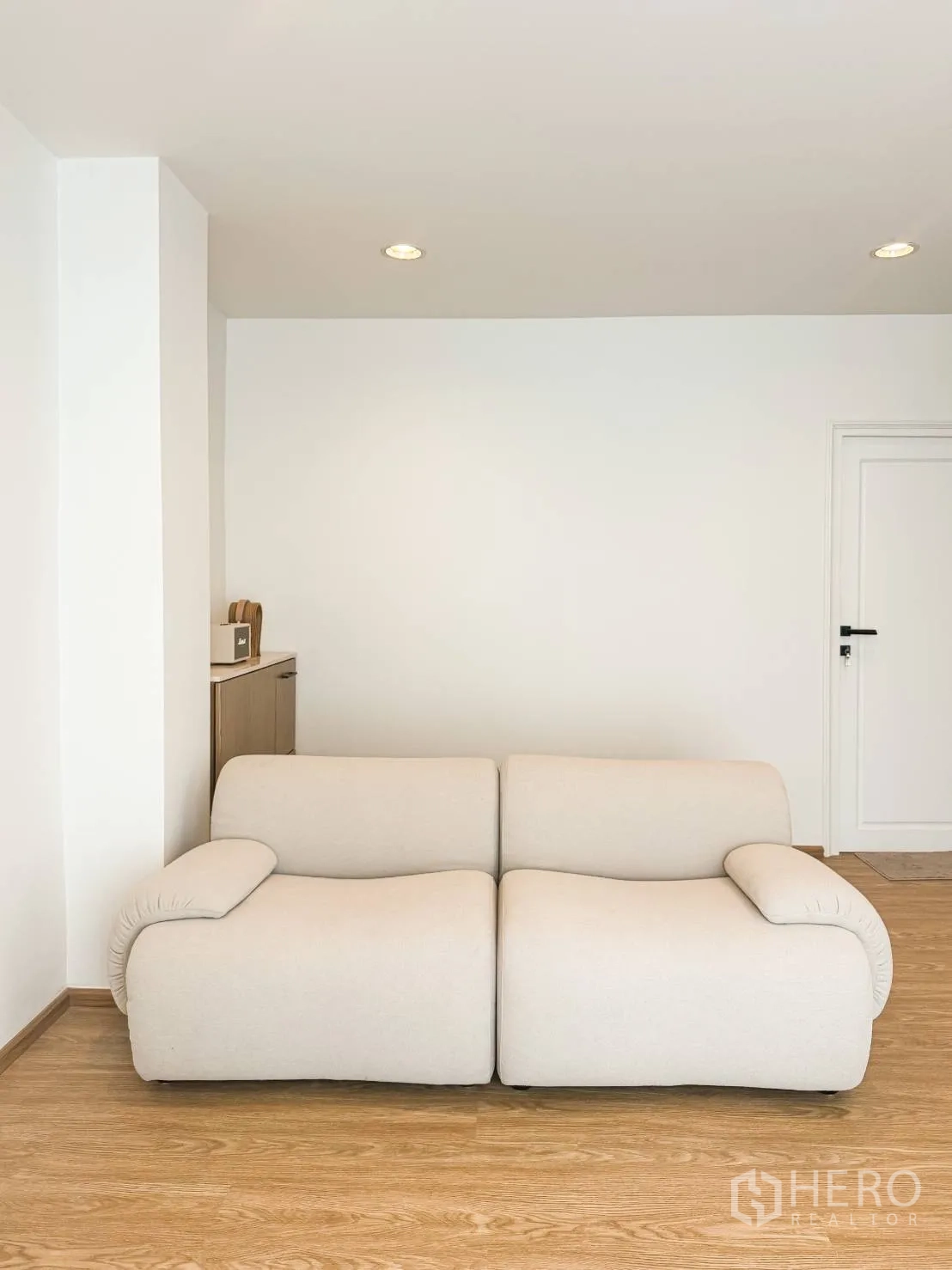ตึกแถว for sale in Watthana, Bangkok - ห้องนั่งเล่นมินิมอลมีโซฟาสองที่นั่งสีครีม พื้นไม้ และผนังสีขาว.