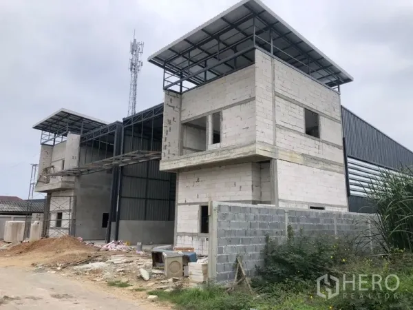 Warehouse for rent in Lam Luk Ka, Pathum Thani - Front exterior of newly built warehouse complex with concrete office blocks and steel roofing.