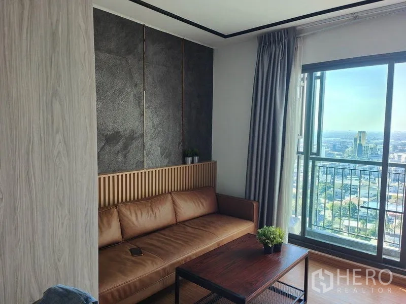 公寓 出租在Khlong Toei, Bangkok - 采光充足的客厅，皮沙发与大窗户，开阔城市景观。