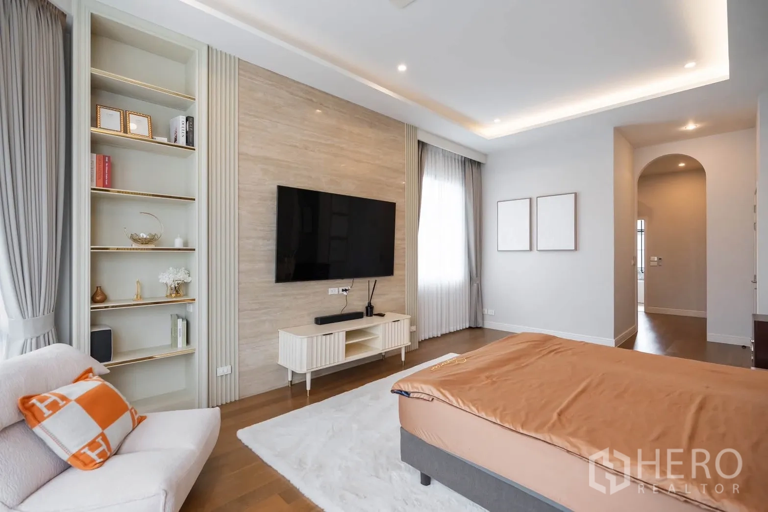 Detached House for rent or sale in Bang Kapi, Bangkok - Master bedroom with TV feature wall, built-in shelves, and large windows with drapes.