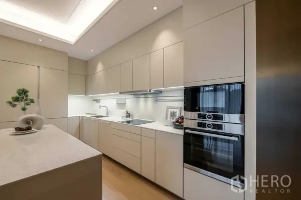 公寓 出售在Pathum Wan, Bangkok - 现代一体式厨房，长台面、充足柜体与双层嵌入式烤箱。