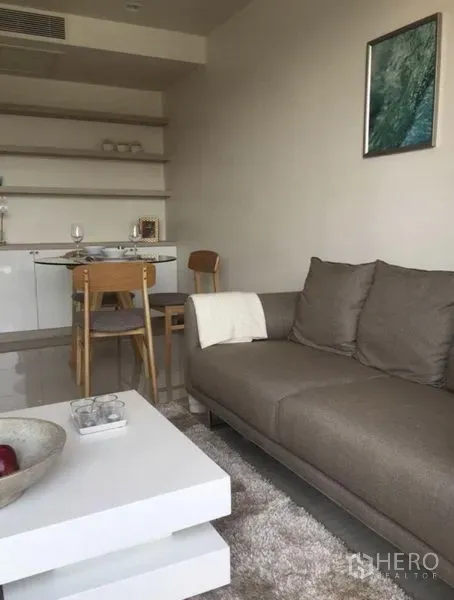 公寓 出租或出售在Watthana, Bangkok - 舒适起居区，灰色沙发、白色茶几与餐桌及壁架
