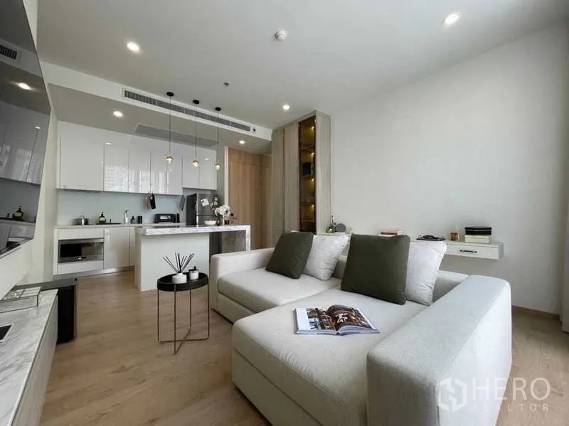公寓 出售在Watthana, Bangkok - 宽敞客餐厨一体，吊灯、亮白橱柜与L型沙发。