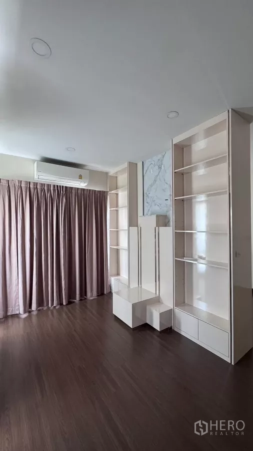 Detached House for rent or sale in Saphan Sung, Bangkok - Upper‑floor multipurpose room with built‑in white shelving, pink drapes and dark wood floors.