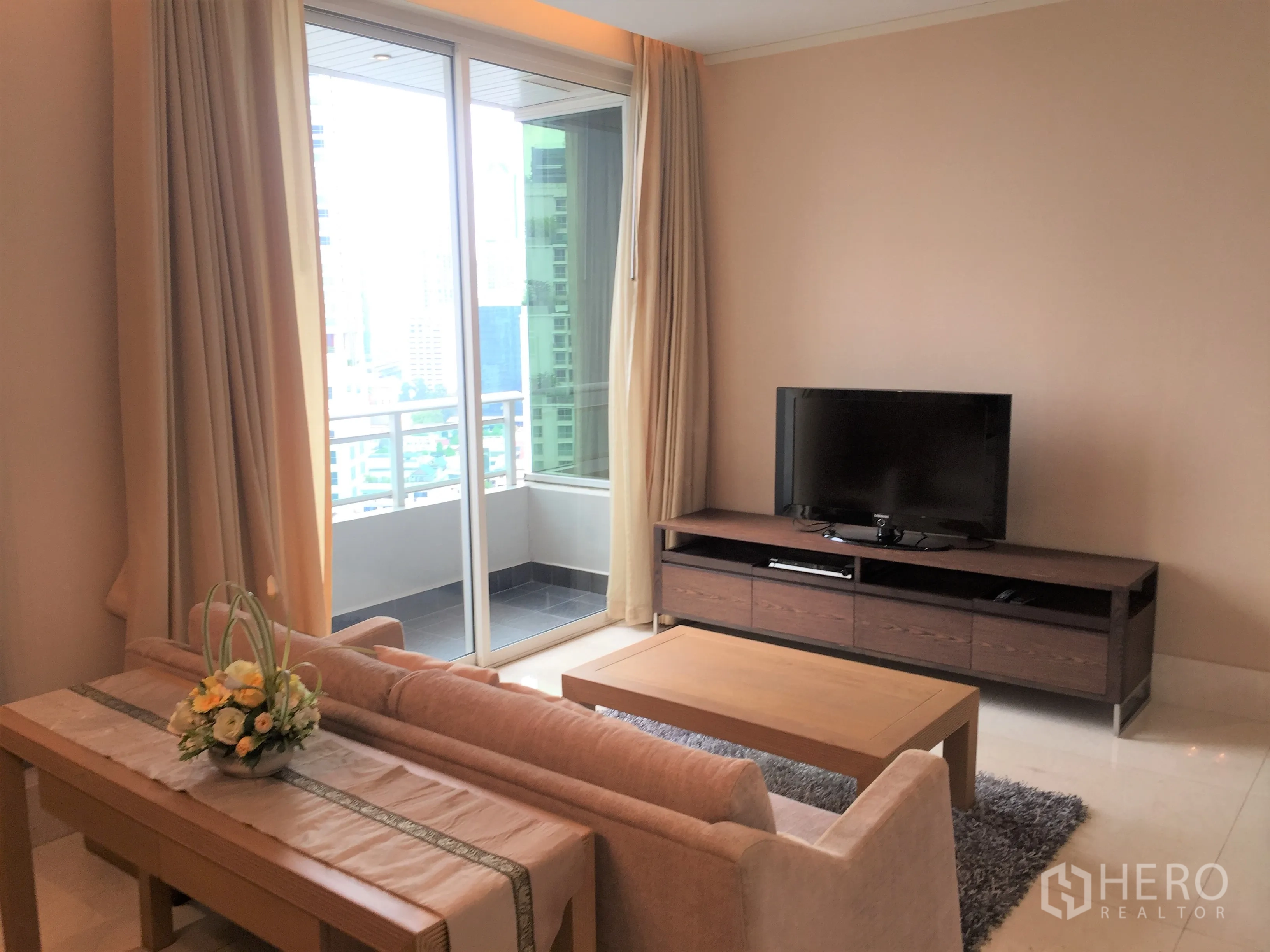 Condominium for rent in Bang Rak, Bangkok - Living room opening to a balcony through sliding glass doors, city views and a media console.