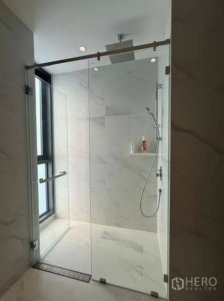 Condominium for rent or sale in Sathon, Bangkok - Glass-enclosed rain shower with window and niche, finished in marble-pattern walls.