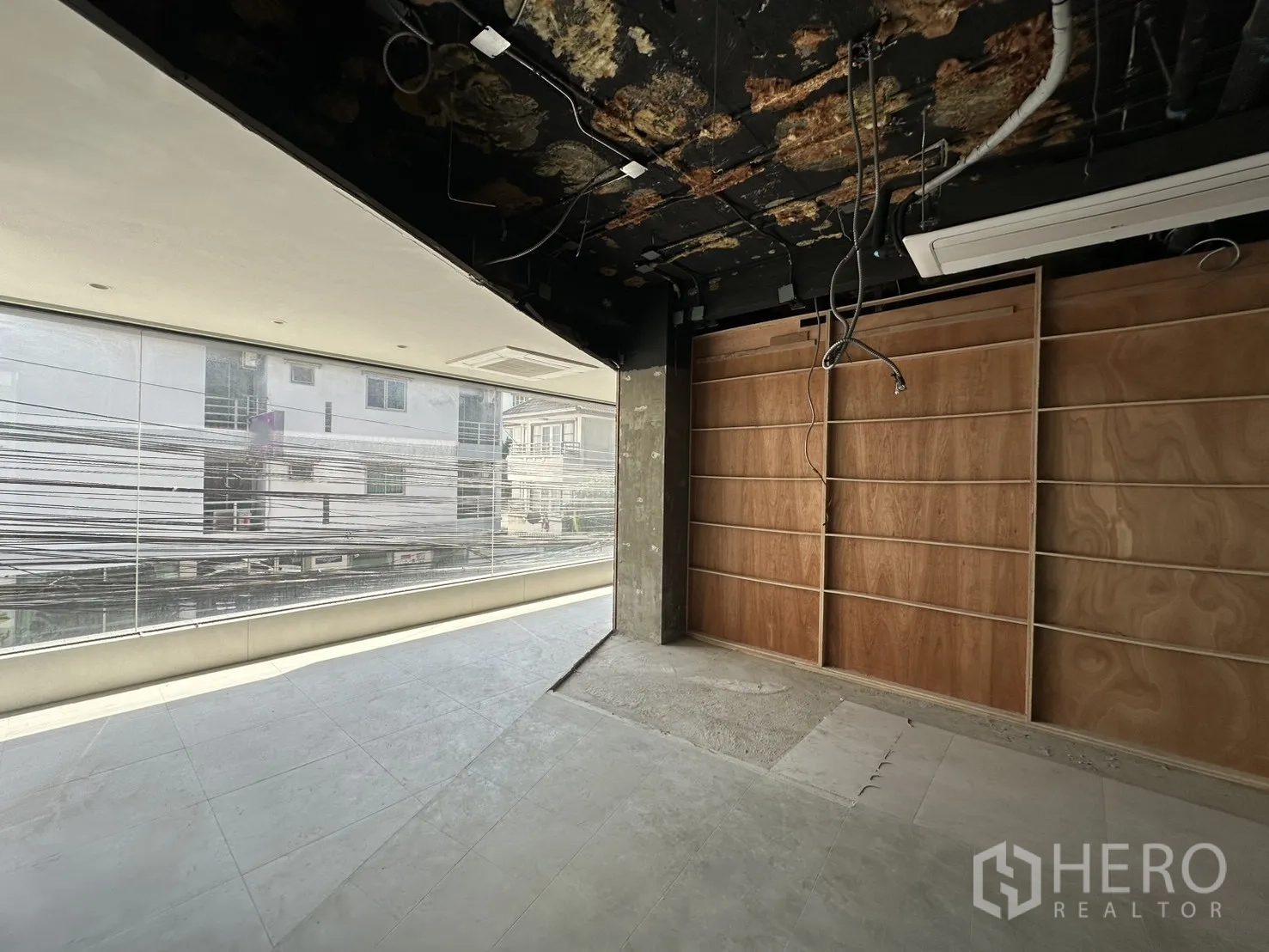 พื้นที่ขายของ for rent in Watthana, Bangkok - มุมห้องมีหน้าต่างกระจกยาวและผนังชั้นวางไม้หันสู่ถนน.