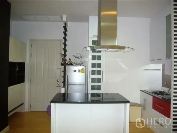 Condominium for rent in Khlong San, Bangkok - Modern white kitchen with island cooktop and stainless range hood.
