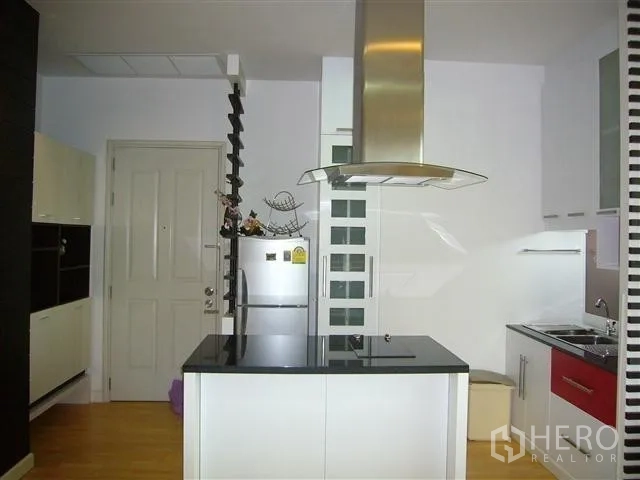 Condominium for rent in Khlong San, Bangkok - Modern white kitchen with island cooktop and stainless range hood.