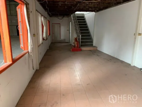 Warehouse for rent in Suan Luang, Bangkok - Ground-floor office area with tiled flooring, internal windows and a staircase leading to the mezzanine.