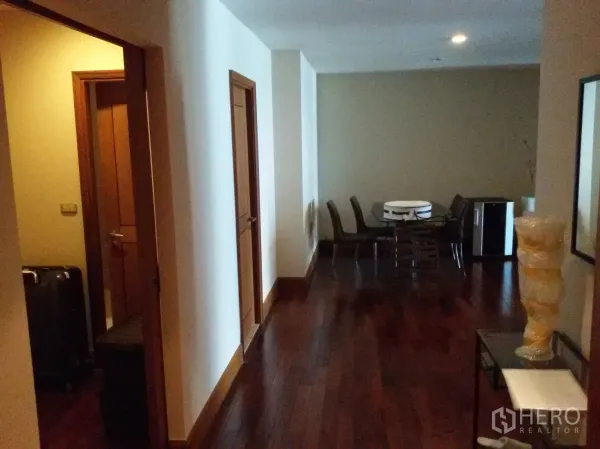 公寓 出租在Sathon, Bangkok - 宽敞走廊与深色木地板，通往带玻璃餐桌的用餐角。
