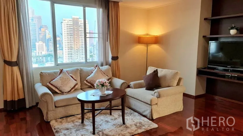 房间 出租在Watthana, Bangkok - 舒适的会客角，双人沙发、扶手椅和茶几，临窗望城景。
