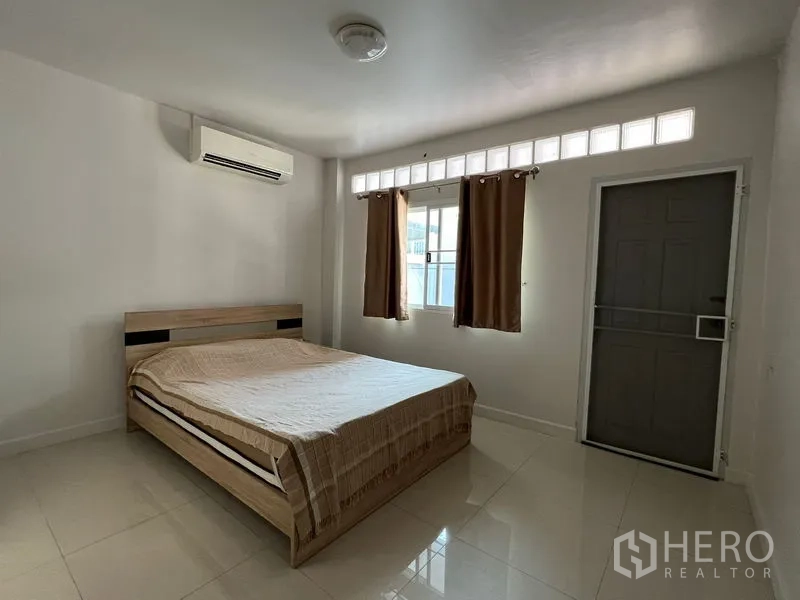 Detached House for rent in Bang Kapi, Bangkok - Bedroom with exterior door, clerestory windows, air conditioning and simple decor.