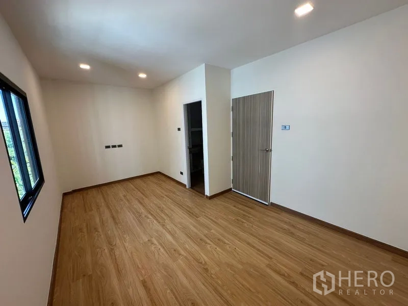 Home Office for rent in Wang Thonglang, Bangkok - Second bedroom with wood floors and door access to an ensuite bathroom.