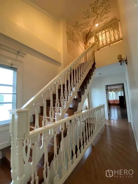 Townhouse for rent or sale in Mueang Samut Prakan, Samut Prakan - Upper landing with ornate staircase and tree mural.