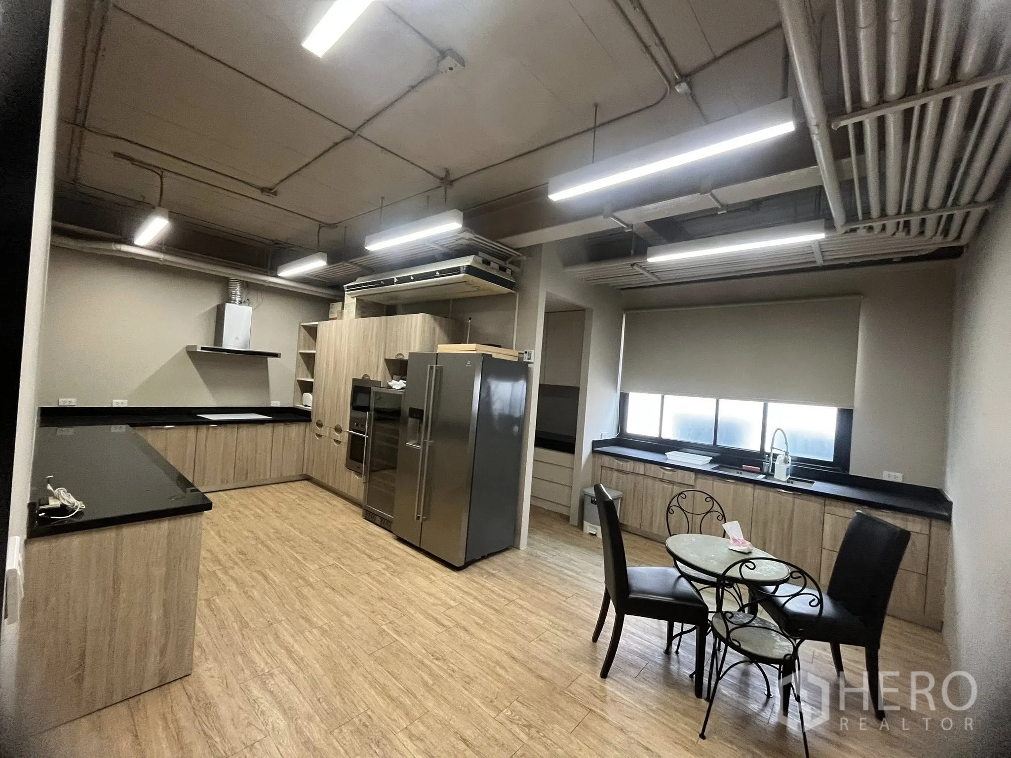 家庭办公室 for rent in Watthana, Bangkok - 大型厨房，木质柜体、黑色台面与不锈钢冰箱。