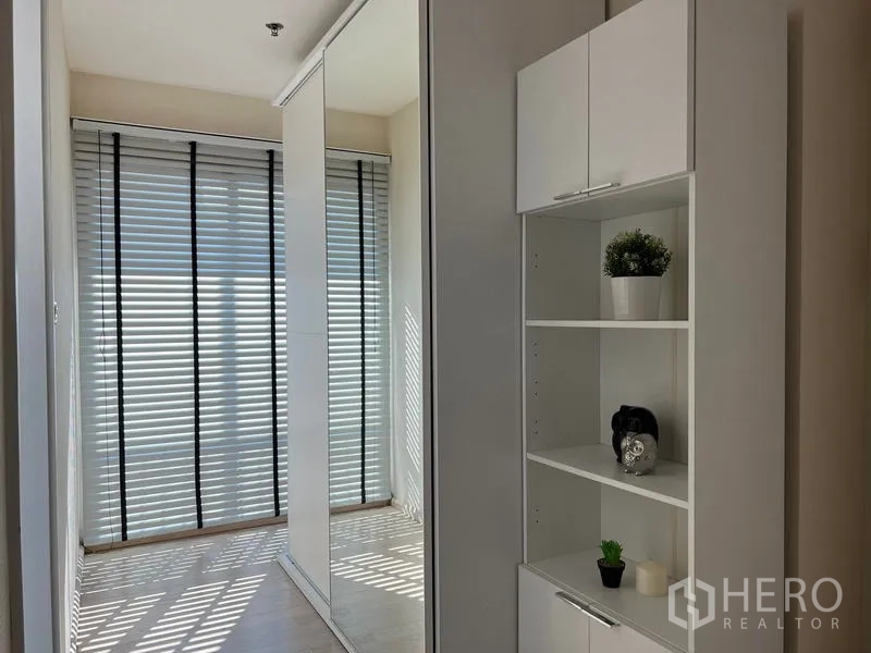 Condominium for rent in Khlong Toei, Bangkok - Hallway with mirrored wardrobe and built-in white shelving.
