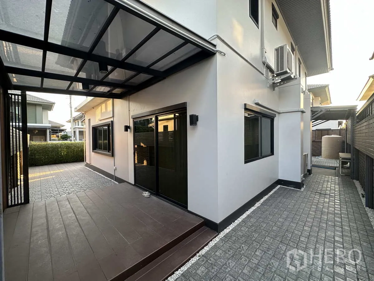 Detached House for rent or sale in Lam Luk Ka, Pathum Thani - Side patio with canopy roof, sliding doors and low‑maintenance paved yard.