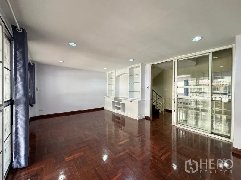 Townhouse for rent or sale in Suan Luang, Bangkok - Living room angle showing sliding glass partition and built-in shelving